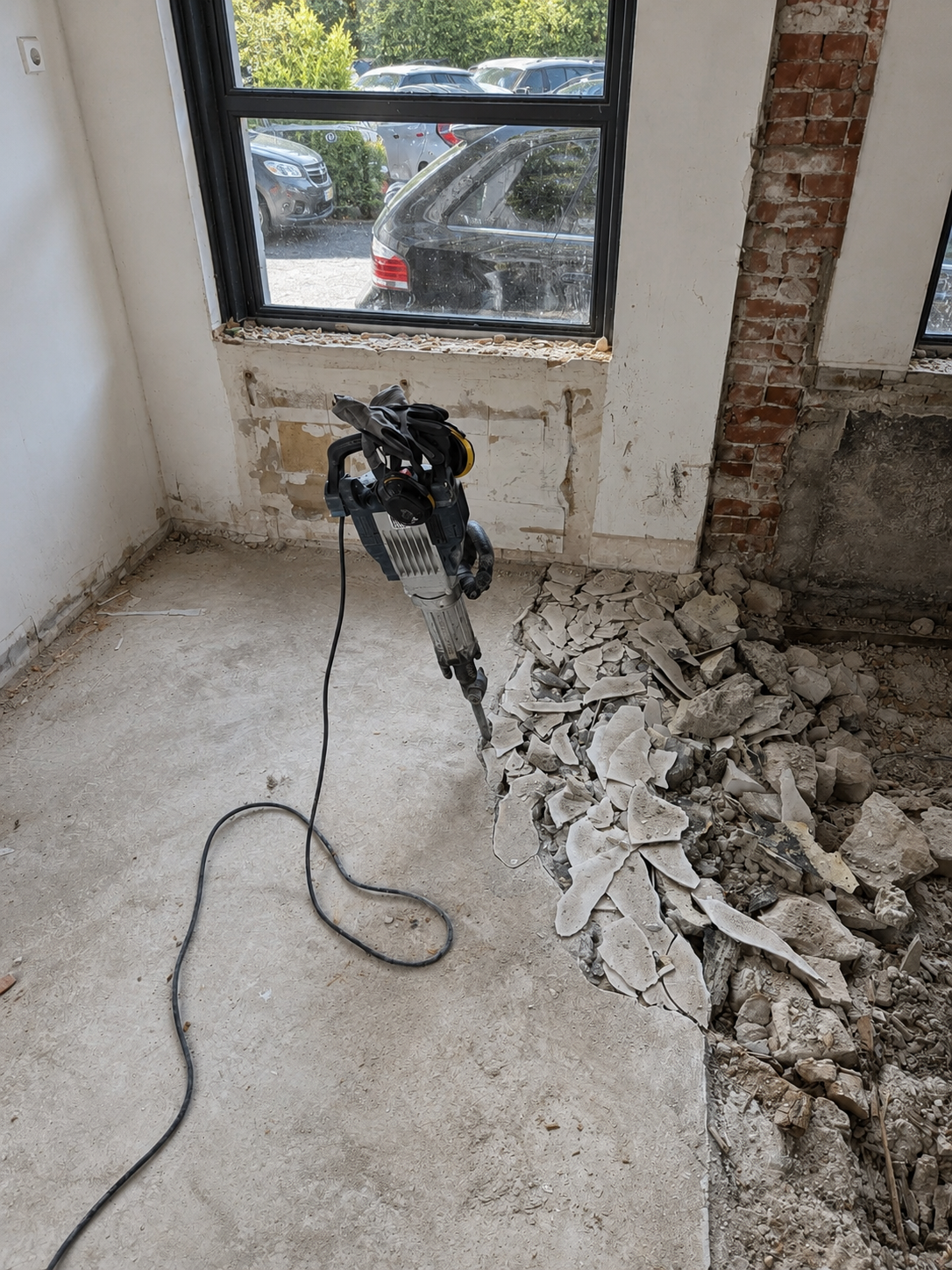 Vakman sloopt een betonnen vloer met een elektrische sloophamer in een woning in Sint-Michielsgestel — 2025